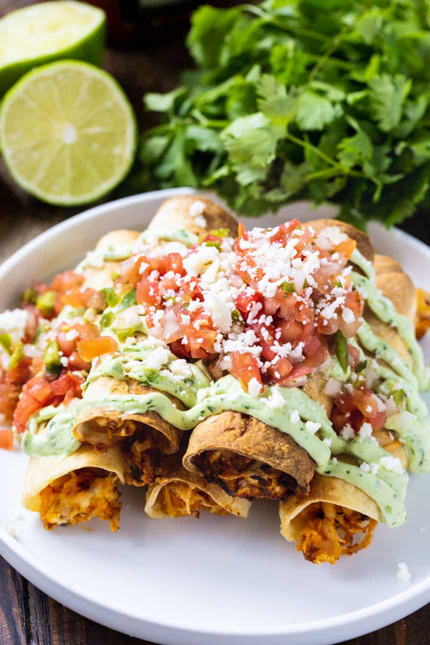 Overhead of Chicken Taquitos with fresh cilantro and limes.