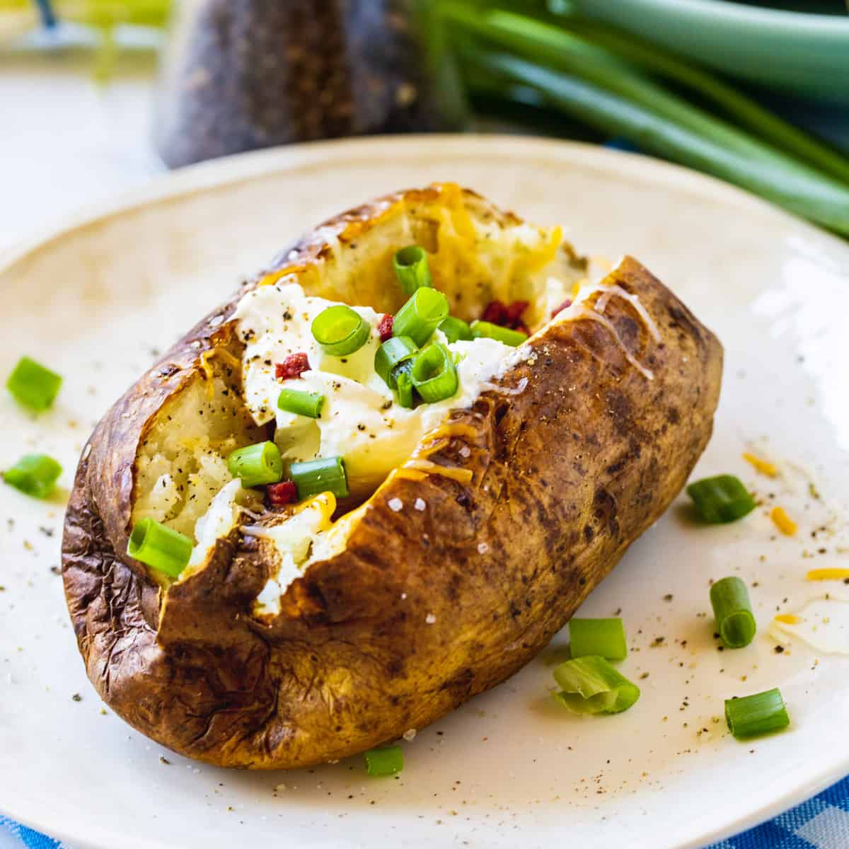 Air Fryer Baked Potato topped with sour cream and green onions.