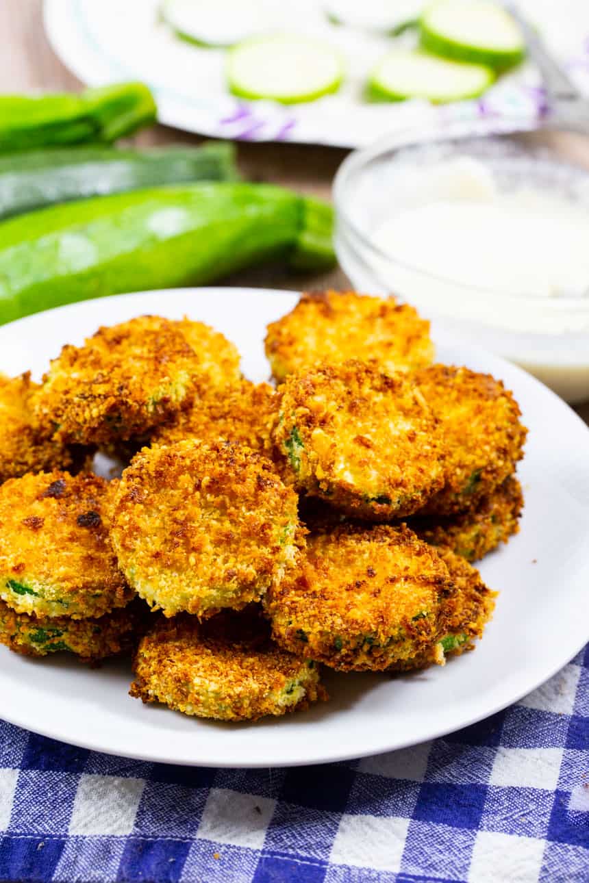 Air Fryer Zucchini Chips on a plate with zucchini in background..