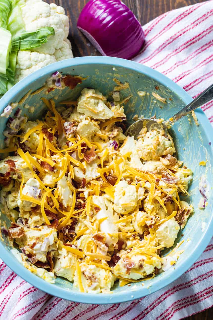 Bacon Cauliflower Salad with lots of shredded cheddar cheese in a serving bowl.
