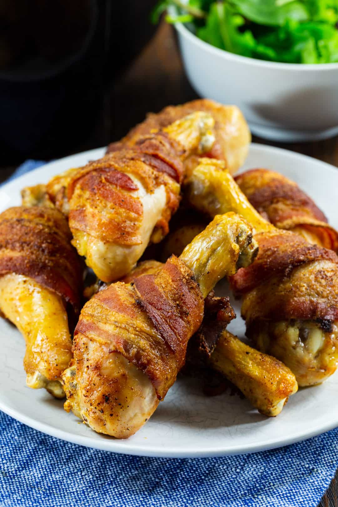 Air Fyrer Bacon-Wrapped Chicken Legs on a white plate.